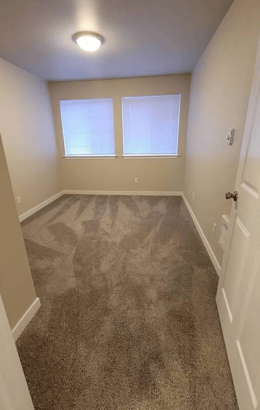 a empty room with a carpeted floor and two windows