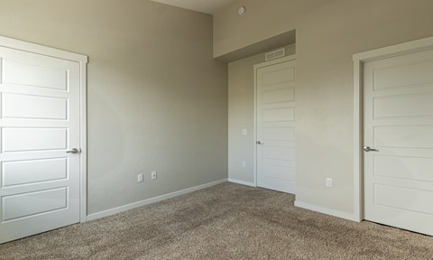 A room with white doors and carpeted floor.