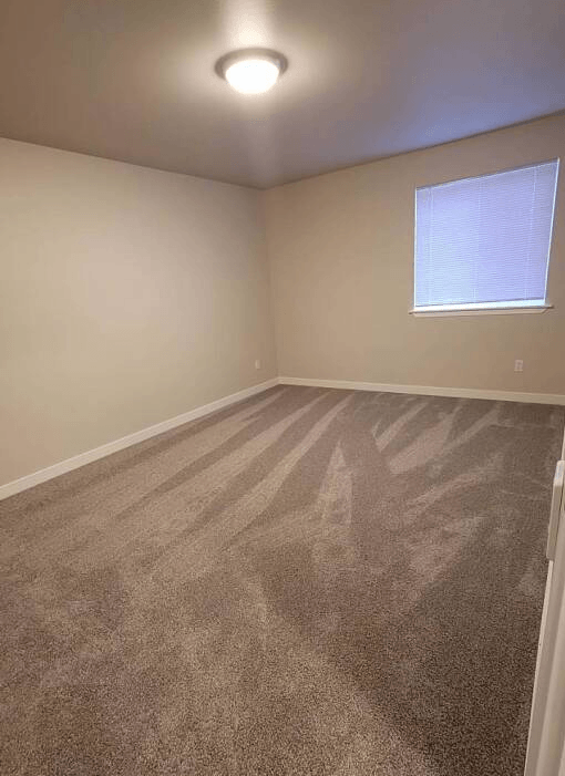 an empty room with carpet and a window