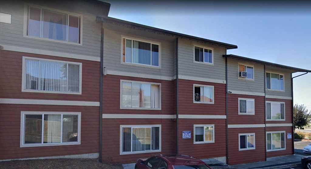Apartment building with a red car parked in front.