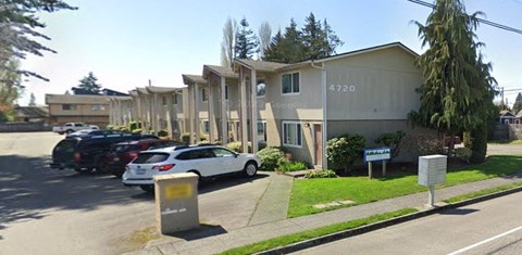 A street view of a residential area with apartment buildings and parked cars.