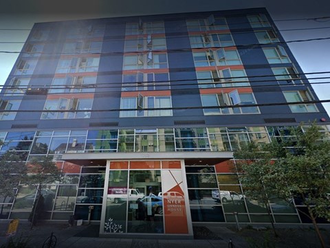 A tall building with a glass facade and a red and white entrance sign.
