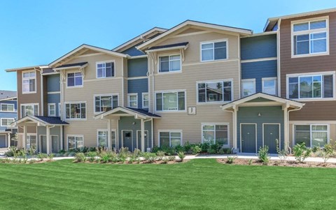 A large, modern apartment building with multiple balconies and doors.