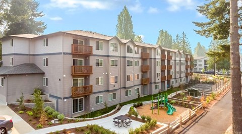 A modern apartment complex with a playground and trees.