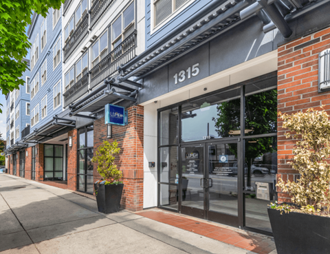 the front of a building with glass doors and a sidewalk