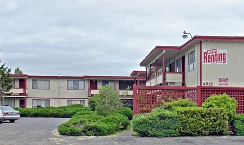 A motel with a sign that says "Now Renting" on the side.