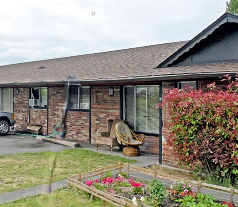 A house with a brown roof and a garden in front.
