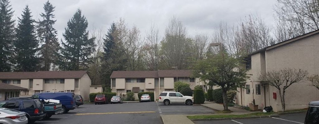 a parking lot with cars in front of an apartment building