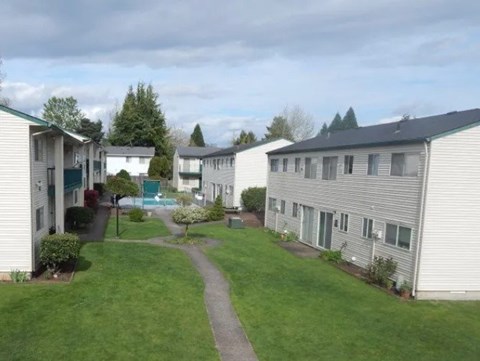 A grassy area with a walking path between two rows of houses.
