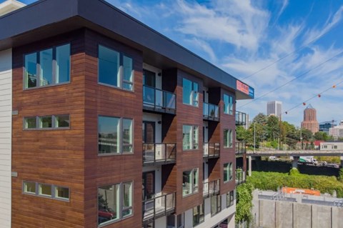 A modern building with wooden panels and balconies overlooks a cityscape.