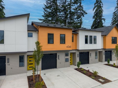 A modern two-story building with a yellow door and a garage door.