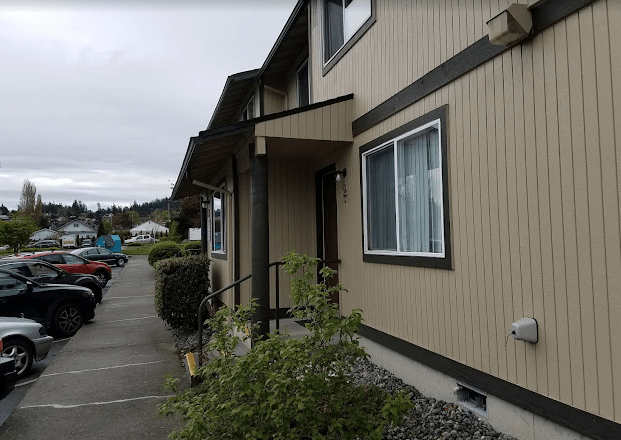 a building with a sidewalk and cars parked in front of it