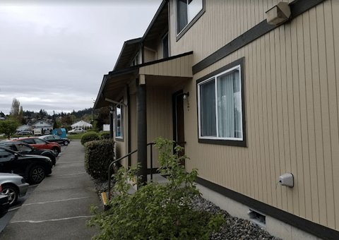 a building with a sidewalk and cars parked in front of it
