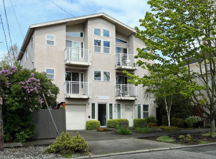a white apartment building with balconies and trees