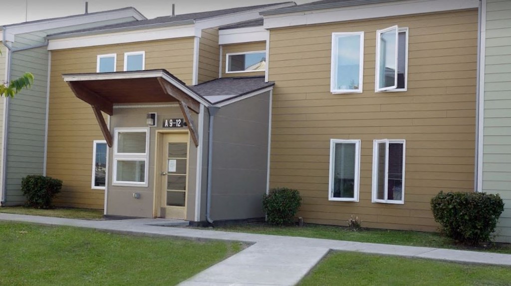 the front of a yellow house with a gray door