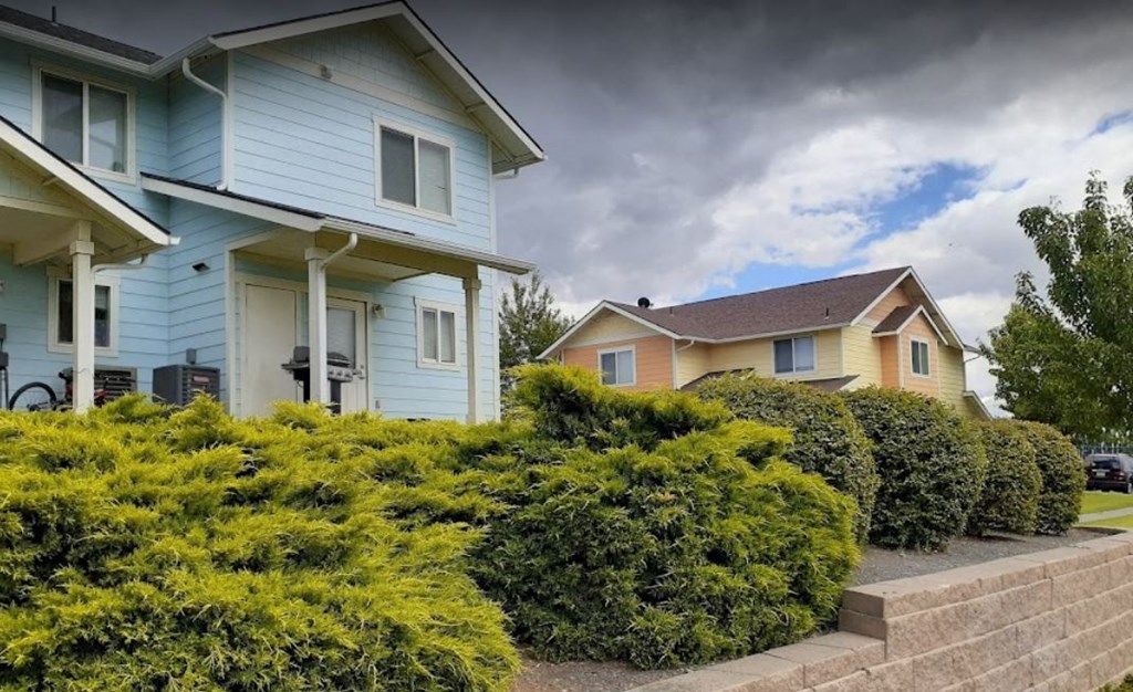a blue house on a hill with a cloudy sky