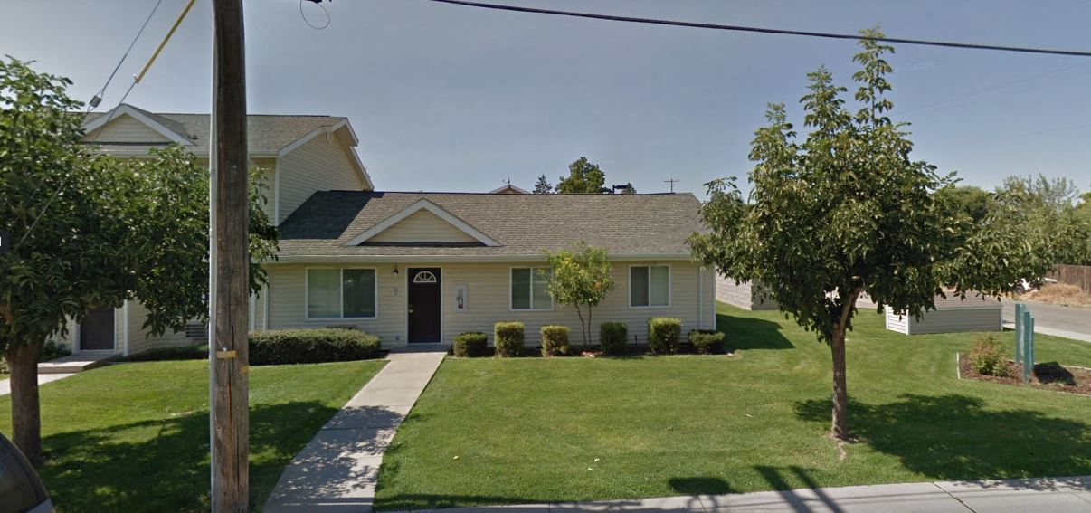 a white house with a lawn and trees