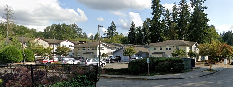 a neighborhood with houses and cars parked in a parking lot