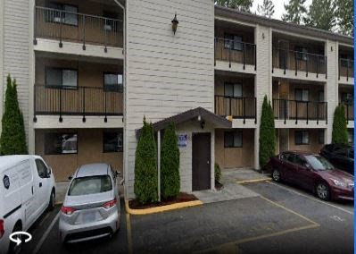 an apartment building with cars parked in a parking lot