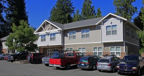 A red truck is parked in front of a two-story building.