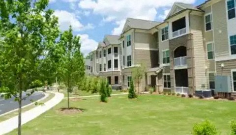 Apartment complex with green lawn and trees.