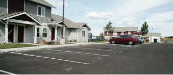 a red car parked in a parking lot in front of houses