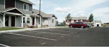 a red car parked in a parking lot in front of houses