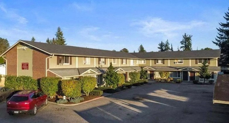 an apartment building with a parking lot and a red car