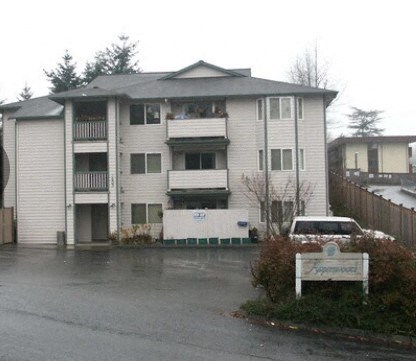 A grey building with a white sign in front of it.