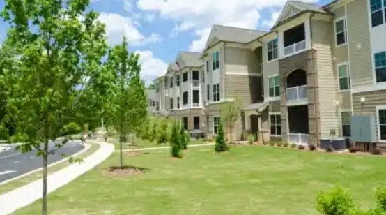 an exterior view of an apartment building with a green lawn