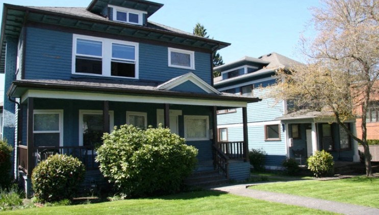A blue house with a white window and a green lawn in front.