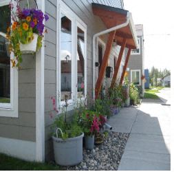 a sidewalk in front of a house with potted plants