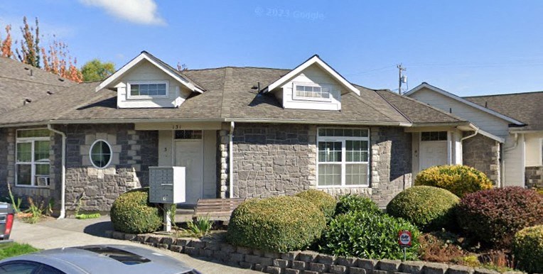 A house with a grey stone facade and a grey roof with a white trim.