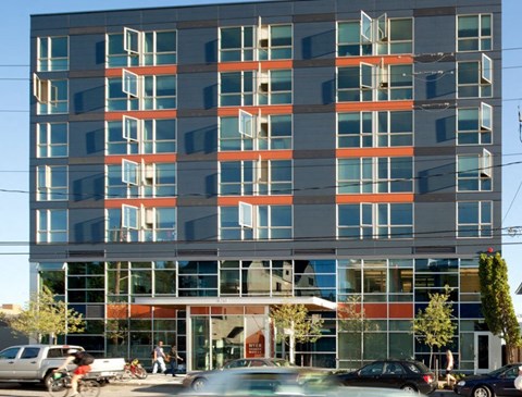 A modern building with a glass facade and a red awning at the entrance.