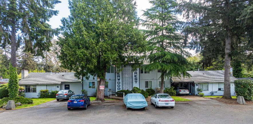 A white house with a blue car parked in front.
