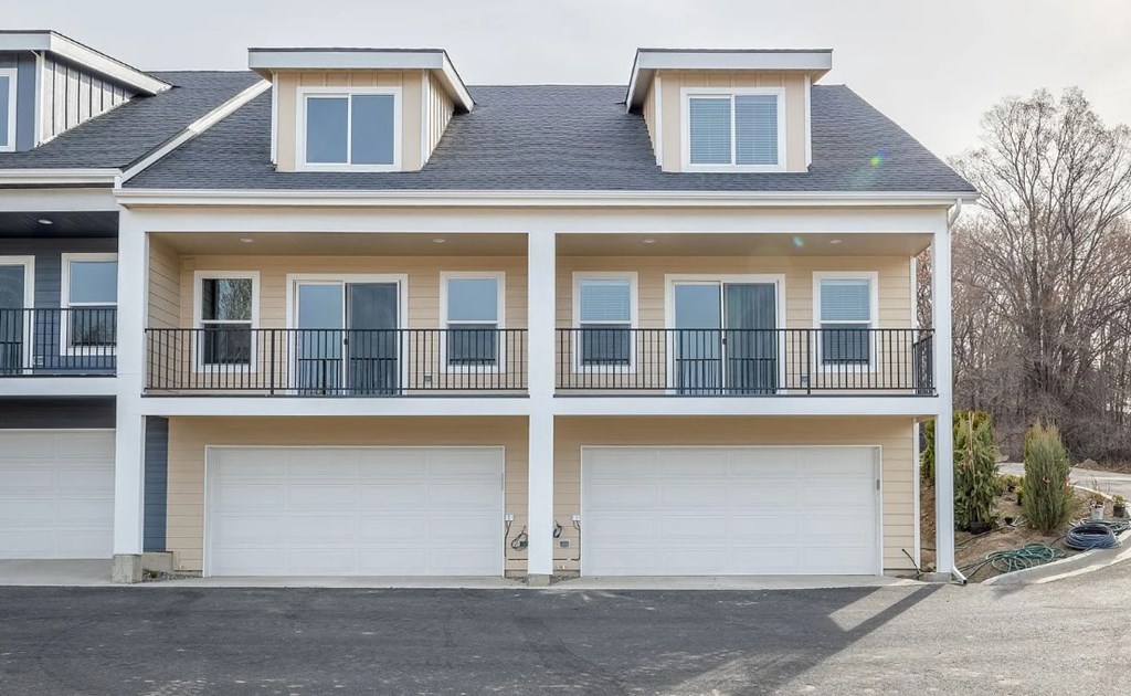A two-story house with a balcony and two garages.