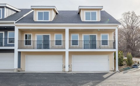 A two-story house with a balcony and two garages.