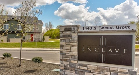 A sign for Enclave stands in front of a house.