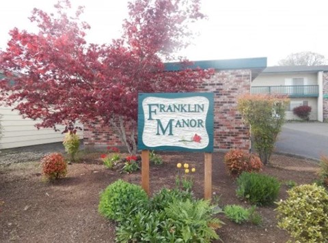 A sign that says Franklin Manor in front of a building.
