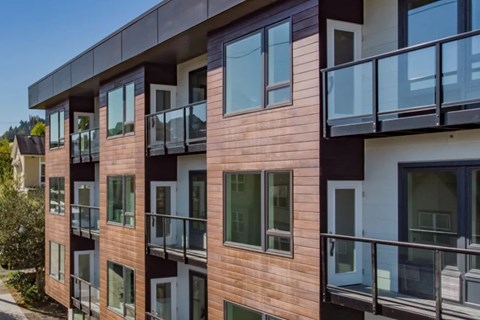 A modern apartment building with balconies and glass doors.