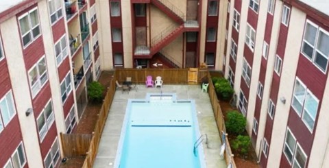 A swimming pool in the middle of a courtyard surrounded by apartment buildings.