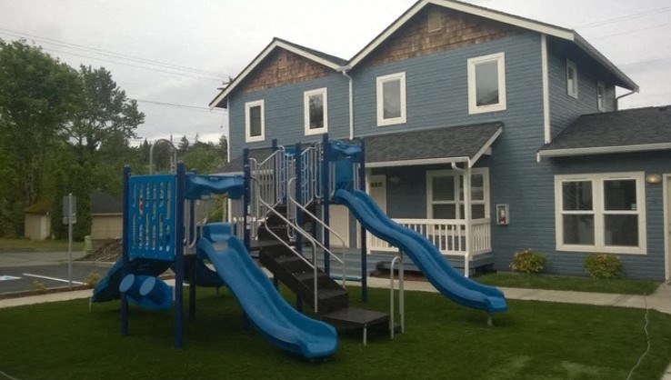 A blue slide in front of a house.