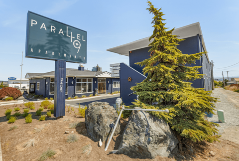 a pine tree in front of a building with a sign that