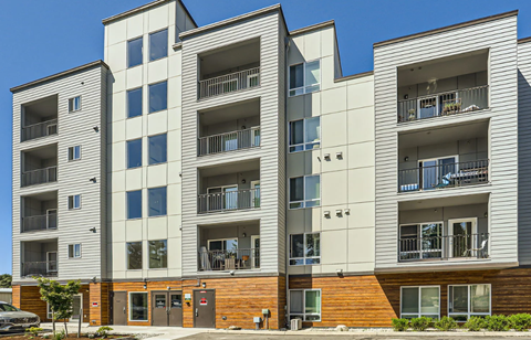 A modern apartment building with balconies and multiple windows.