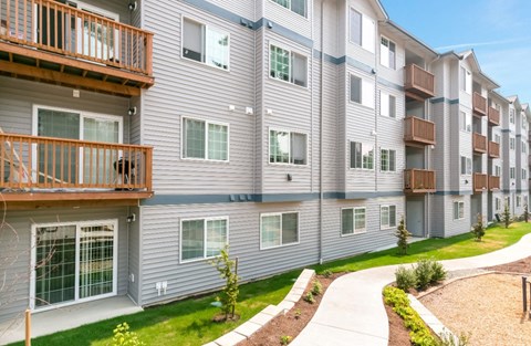 Apartment complex with balconies and greenery in the front.