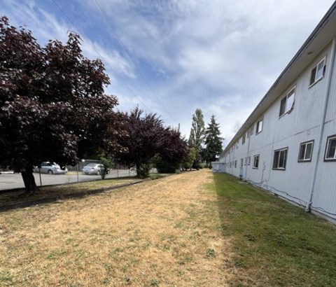 A white building with a fence and trees in front.