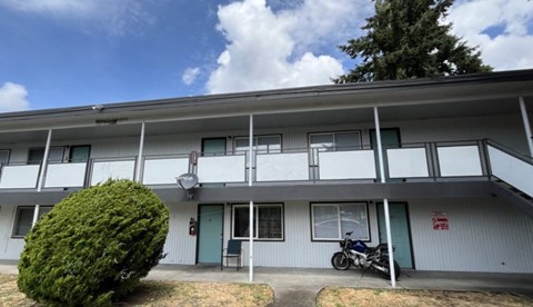A motorcycle is parked on the porch of a building with a green door.
