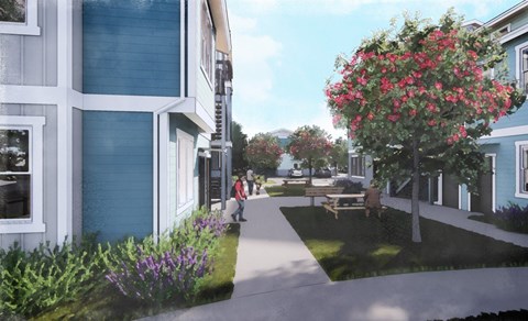 A street view of a residential area with a blue building on the left and a tree with pink flowers on the right.