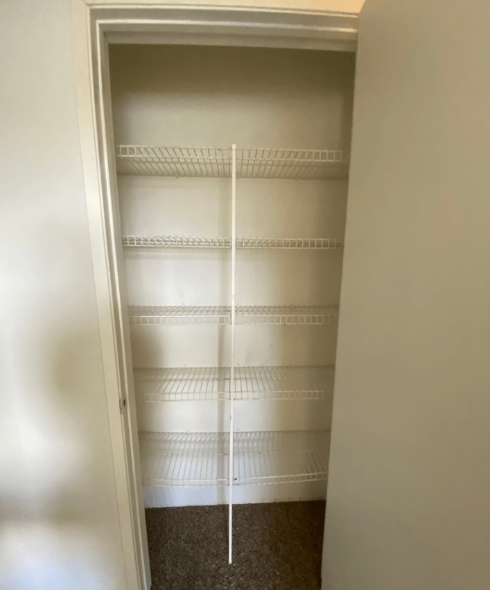 a closet with white shelves and a white door