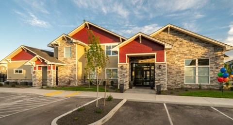 A building with a red roof and stone walls has a black door and windows.